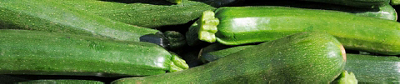 A large pile of fresh, whole green zucchinis with small green stems.