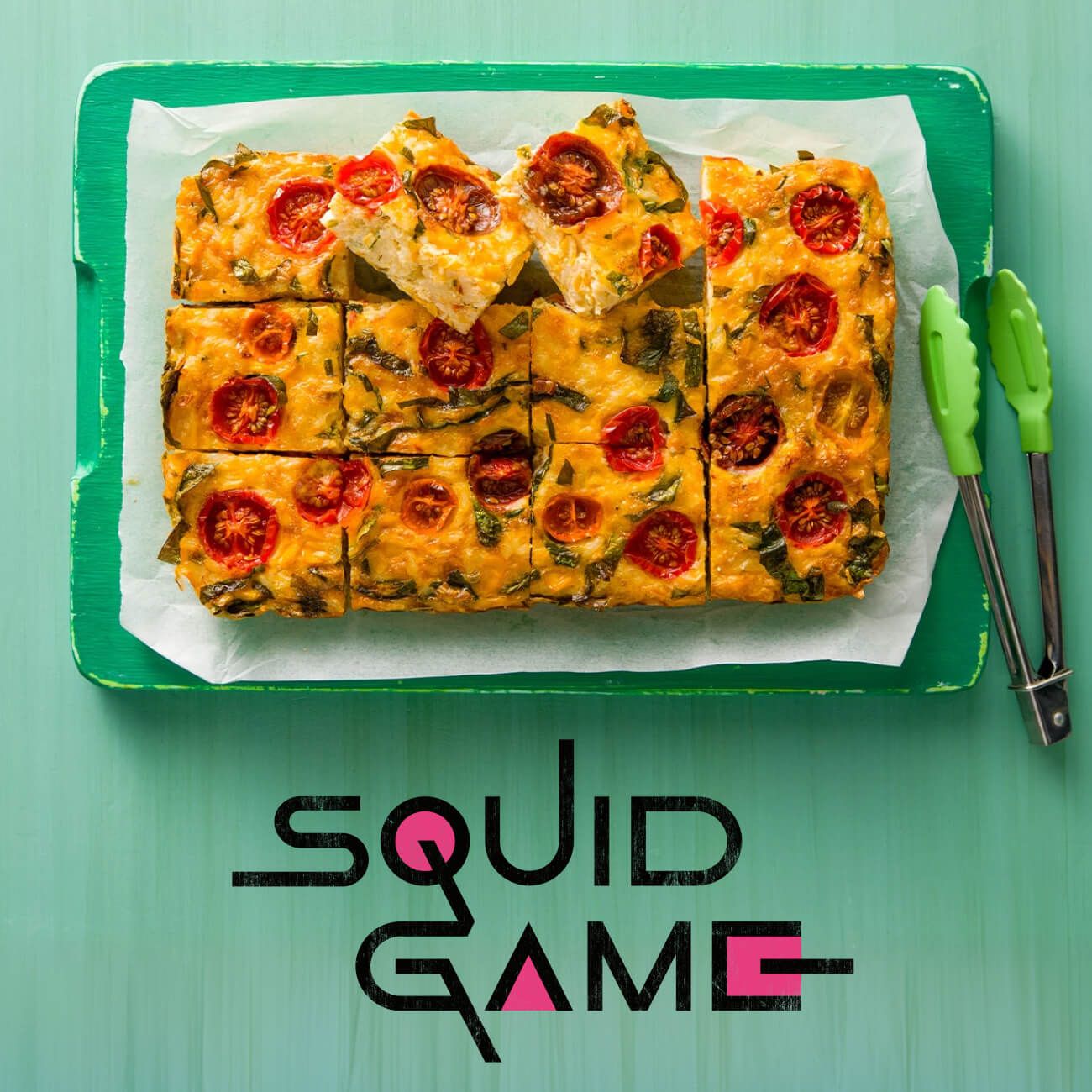 A vegetable frittata with cherry tomatoes on a green board, featuring the "SQUID GAME" logo.
