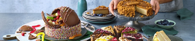 An assortment of gourmet cakes, including a chocolate piñata cake filled with lollies and various sliced dessert wedges.