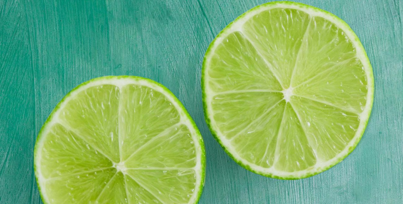 Lime cut halves on a green wooden background