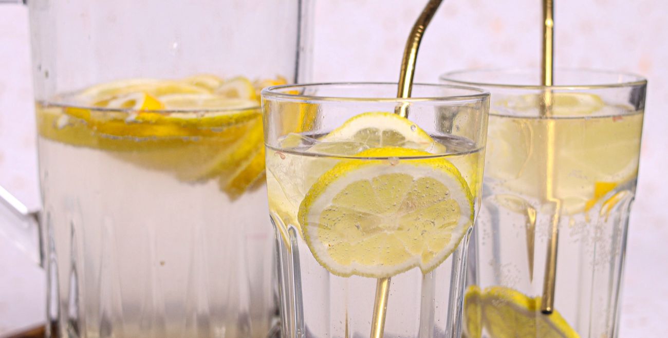 Water with lemon slices in glasses and a pitcher