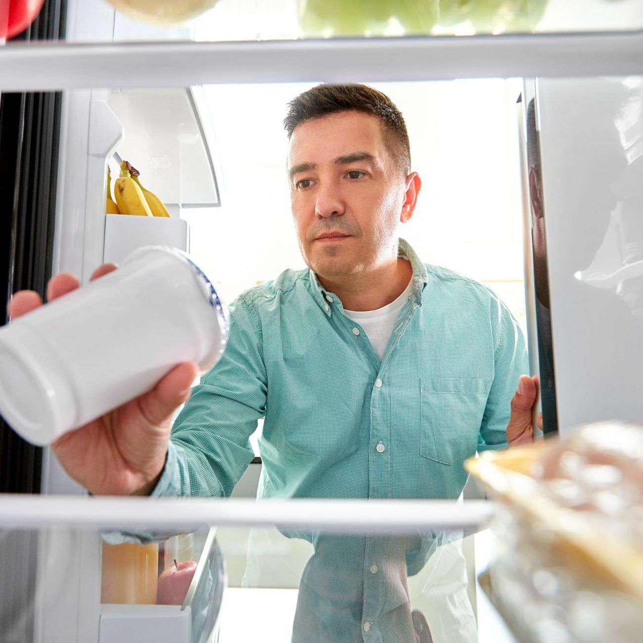 Man checking use-by date of item in fridge
