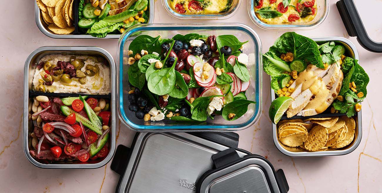 Collection of Fissler Glass containers with meal prep recipes including salads, dips, bakes and more.