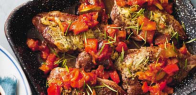 Baked meat cutlets topped with melted cheese, diced tomatoes and fresh rosemary sprigs in a black speckled pan.