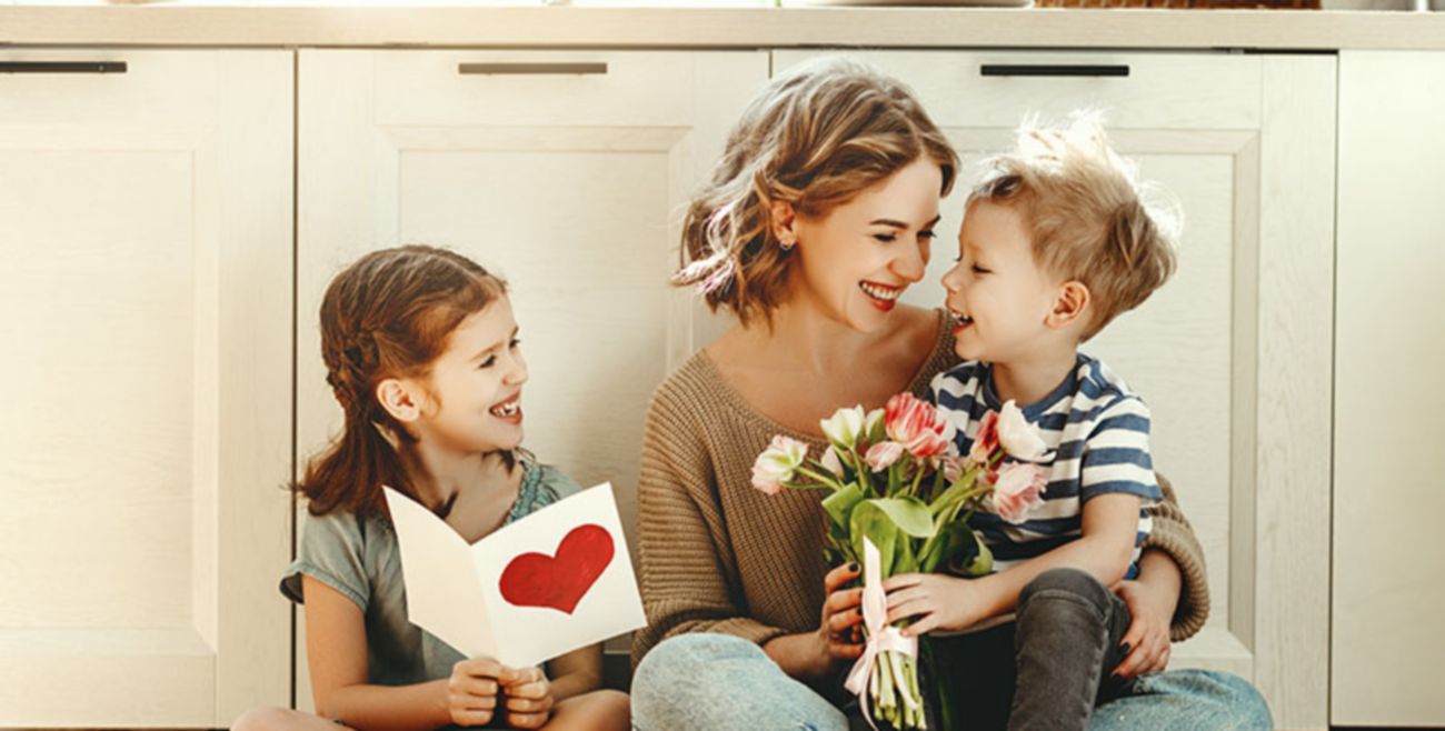 Little children congratulating mother in kitchen