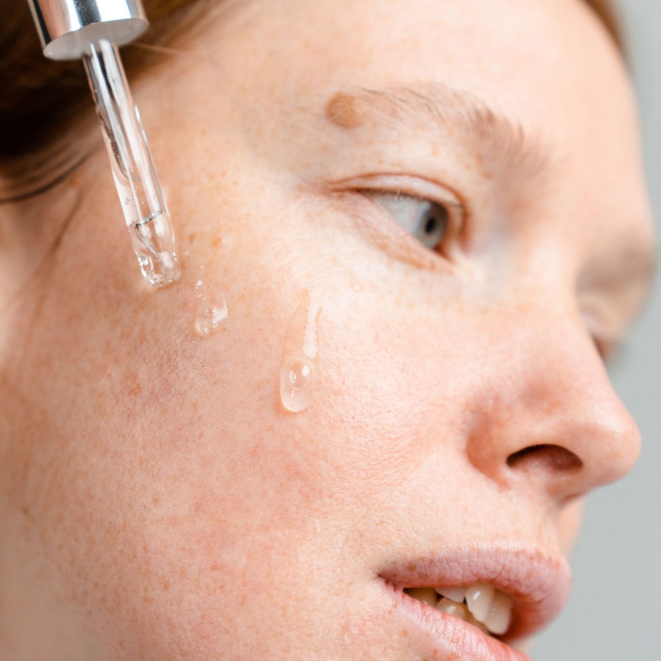 A woman applies serum to her face