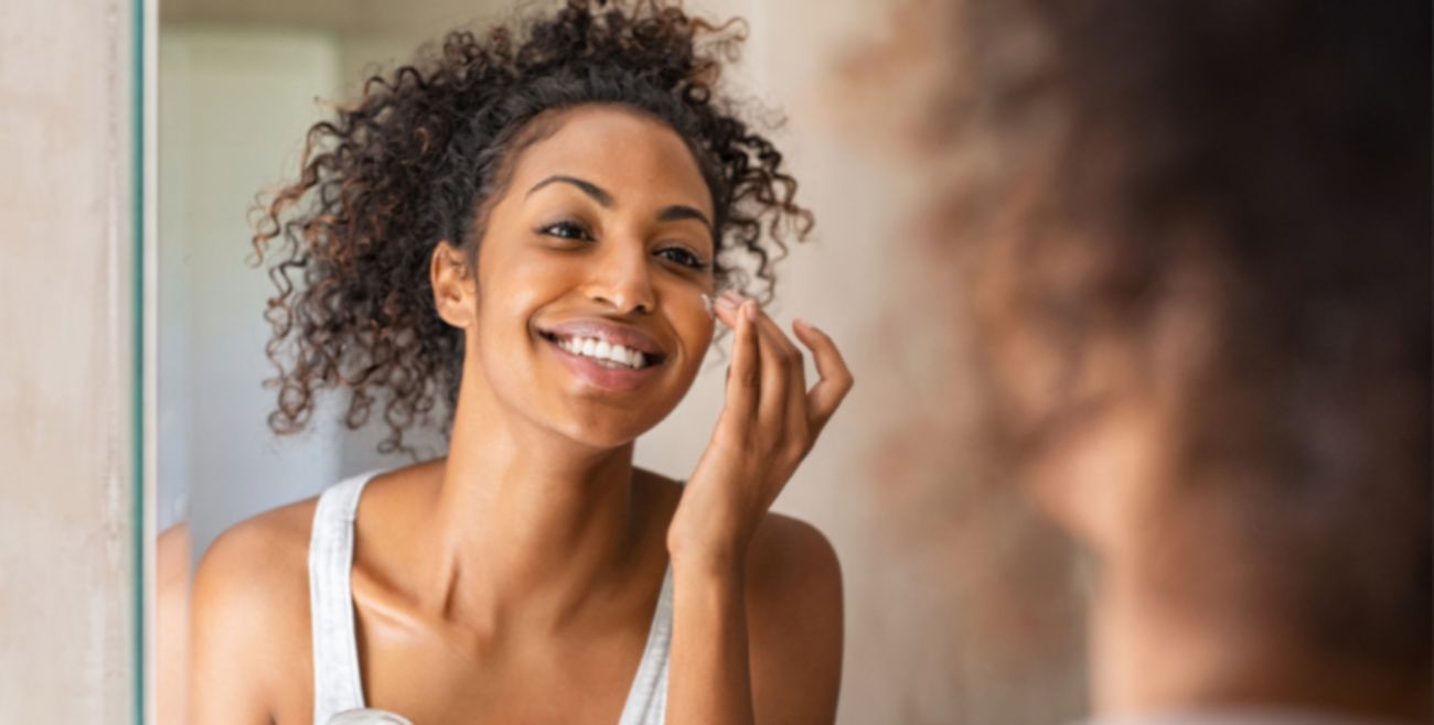 Lady applying moisturiser in the bathroom mirror